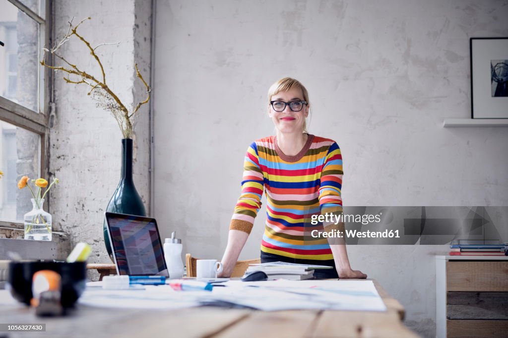 Portrait of smiling woman at desk in a loft