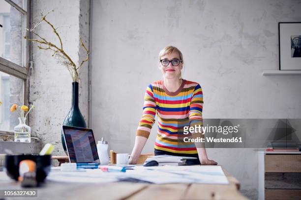 Portrait of smiling woman at desk in a loft