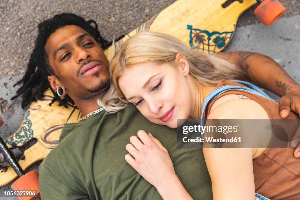 portrait of multicultural young couple with longboard relaxing together - couple skating stock pictures, royalty-free photos & images