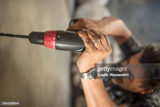 man drilling into wall, close-up - trapano elettrico foto e immagini stock