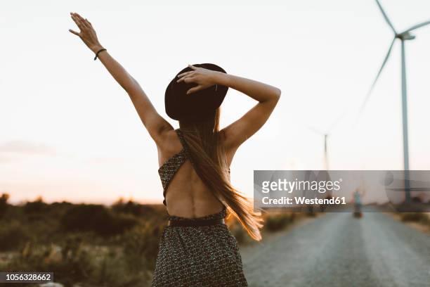 back view of young woman on rural road at sunset - welcome back stock-fotos und bilder