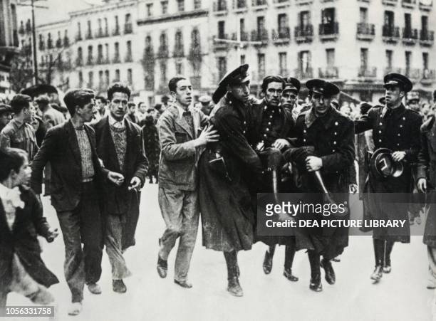 Guardia de Asalto injured during a street clash being carried from the field by his comrades Barcelona, Spain, Spanish Civil War, 20th century.