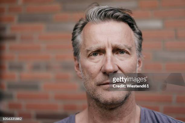 portrait of serious mature man in font of brick wall - männer über 40 stock-fotos und bilder