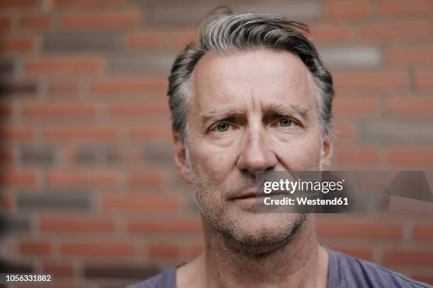 portrait of serious mature man in font of brick wall - alleen één oudere man stockfoto's en -beelden