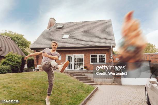 mature man kicking away garden gnome in front of his home - zwerg stock-fotos und bilder