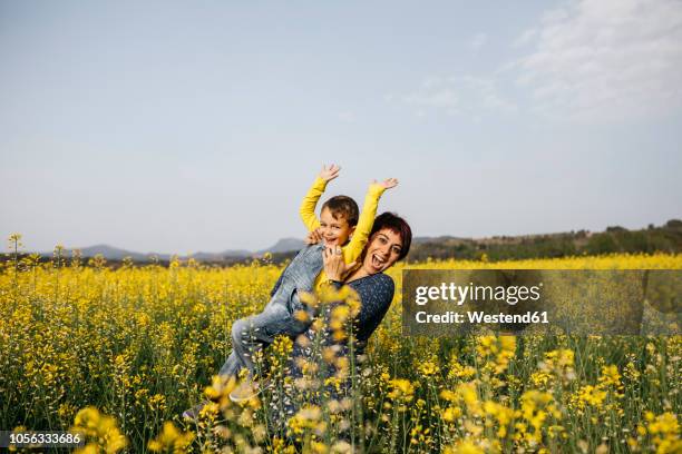 spain, portrait of happy mother and her little son up standing in rape field - frühling pollen stock-fotos und bilder