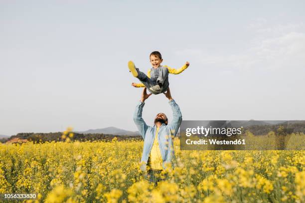 spain, father and little son having fun  together in a rape field - boy throwing stock-fotos und bilder
