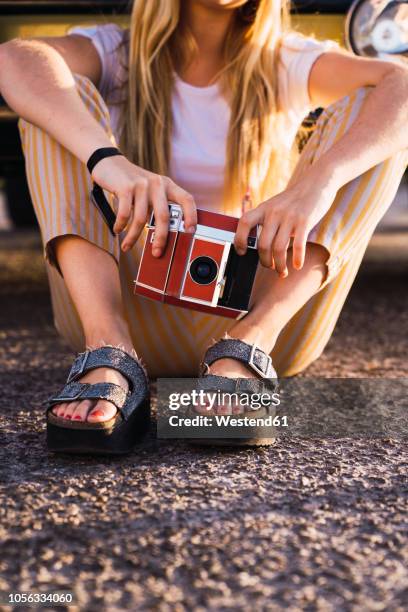 young woman holding vintage camera sitting outside at a van - open toe stock pictures, royalty-free photos & images