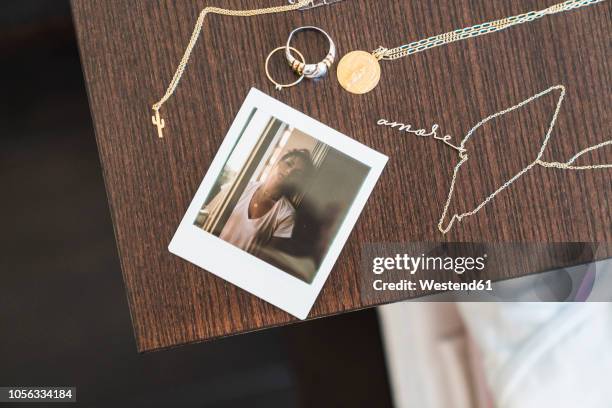 instant photo of young woman next to jewelry on wooden table - necklace stock-fotos und bilder