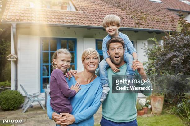 portrait of happy family with two kids in front of their home - stupore esterno foto e immagini stock