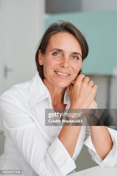 portrait of mature businesswoman wearing white blouse - white blouse stock-fotos und bilder