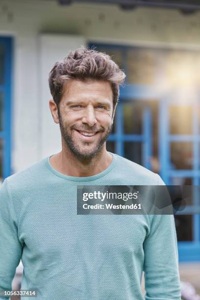 portrait of smiling man in front of house with blue window - 35 39 jahre stock-fotos und bilder