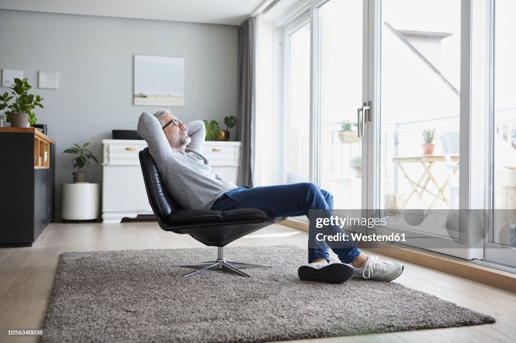 Mature man relaxing on leather chair in his living room