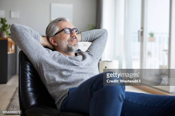 portrait of mature man relaxing at home - tevreden stockfoto's en -beelden