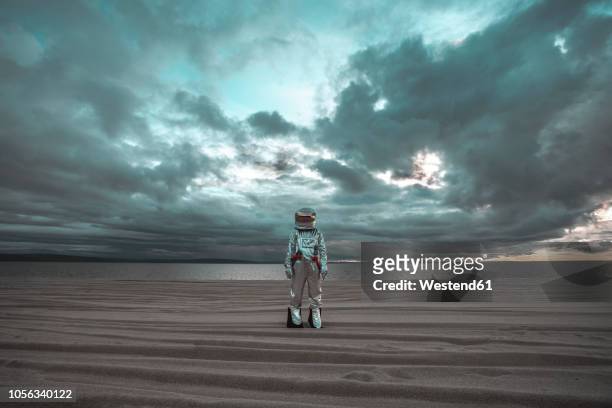 spaceman standing alone at lake on nameless planet - space man on mars imagens e fotografias de stock