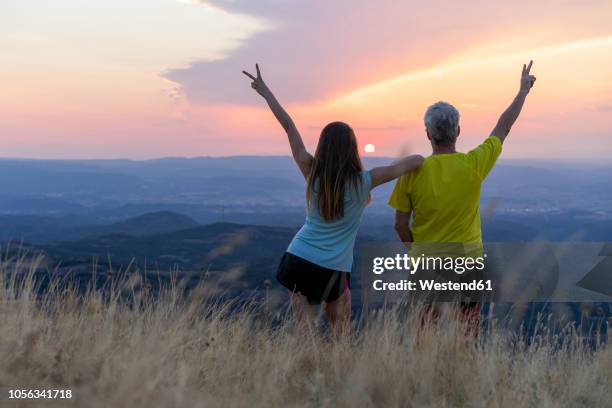 spain, catalonia, montcau, happy senior father and adult daughter looking at view from top of hill during sunset - old man young woman stockfoto's en -beelden