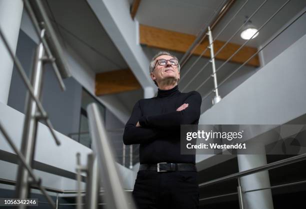 confident senior businessman standing in office hallway - low angle view man stock pictures, royalty-free photos & images