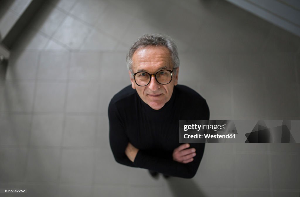 Smiling senior businessman looking up on office hallway