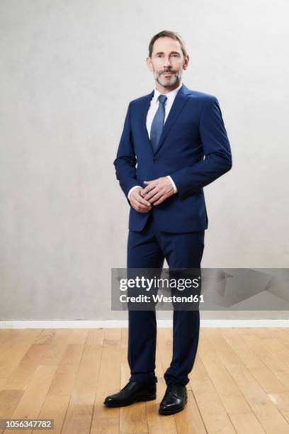 businessman wearing dark blue suit - man standing against grey background foto e immagini stock