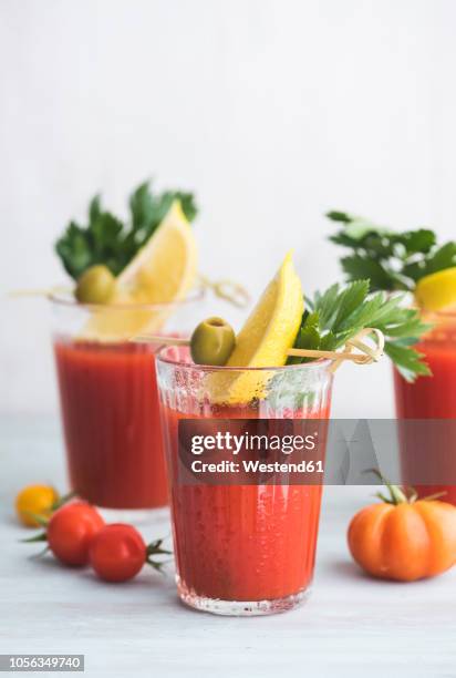 glasses of fresh spicy tomato juice with cellery garnished with lemon slice, green olive and parsley - tomato juice stock pictures, royalty-free photos & images