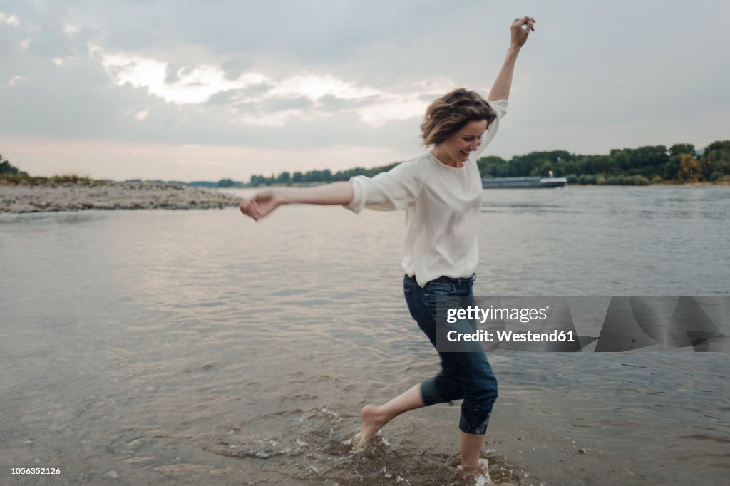 Laughing woman running at the riverside