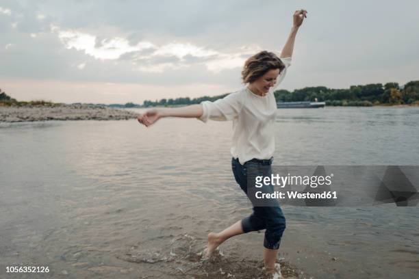 laughing woman running at the riverside - mature woman in water stock pictures, royalty-free photos & images