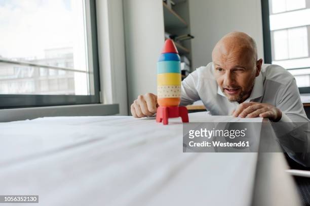 businessman playing with toy rocket in office - scientific development and splendid achievements stock pictures, royalty-free photos & images