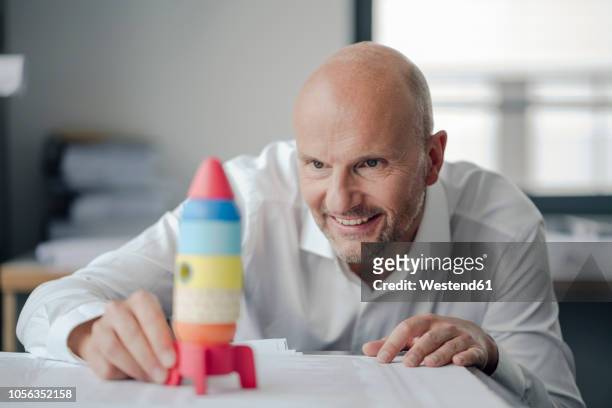 businessman playing with toy rocket in office - scientific development and splendid achievements stock pictures, royalty-free photos & images