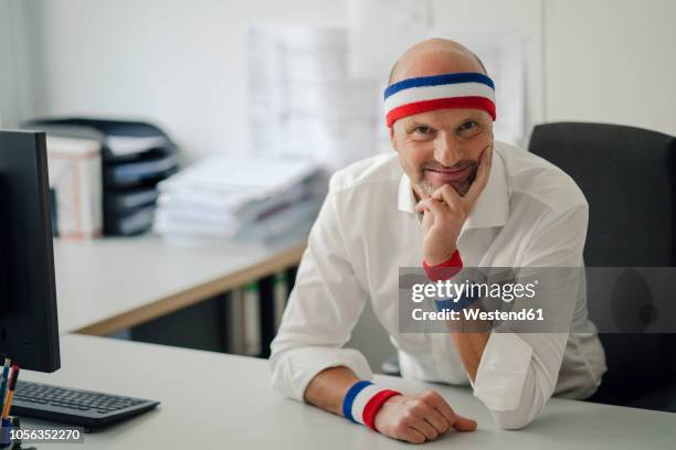businessman sitting in office, wearing sweat bands - zweetband stockfoto's en -beelden
