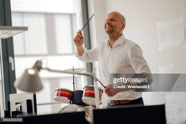 businessman making noise with drums in his office - trommel stock-fotos und bilder