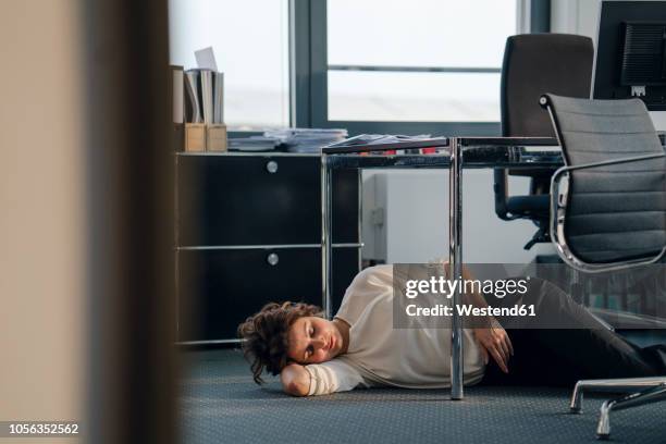 tired businesswoman sleeping on floor under her desk - escaping office stock pictures, royalty-free photos & images