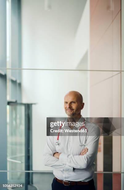 doctor standing in hospital with stethoscope around his neck - determination doctor stock pictures, royalty-free photos & images