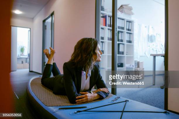 businesswoman lying on paddle board, daydreaming in office - escaping office stock pictures, royalty-free photos & images