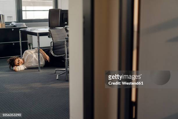 tired businesswoman sleeping on floor under her desk - escaping office stock pictures, royalty-free photos & images
