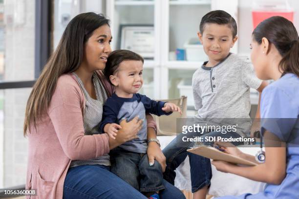 mother visits the pediatrician with her sons - crying sibling stock pictures, royalty-free photos & images