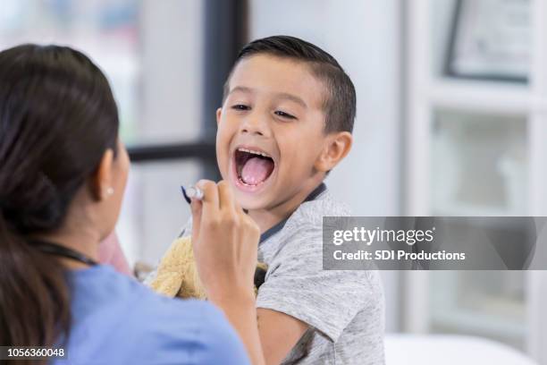 kleiner junge öffnet den mund für kehle prüfung am kinderarzt - throat exam stock-fotos und bilder