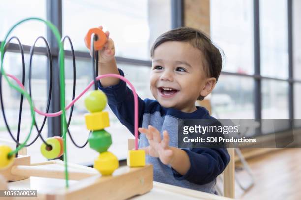 toddler boy enjoys playing with toys in waiting room - preschool stock pictures, royalty-free photos & images