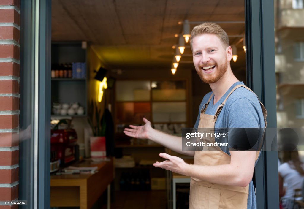 Happy business owner welcoming customers at a cafe