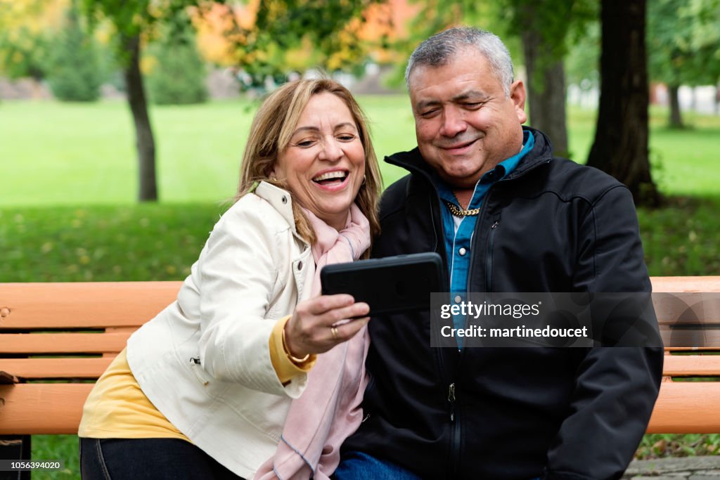 Senior Latin American couple taking a selfie outdoors.