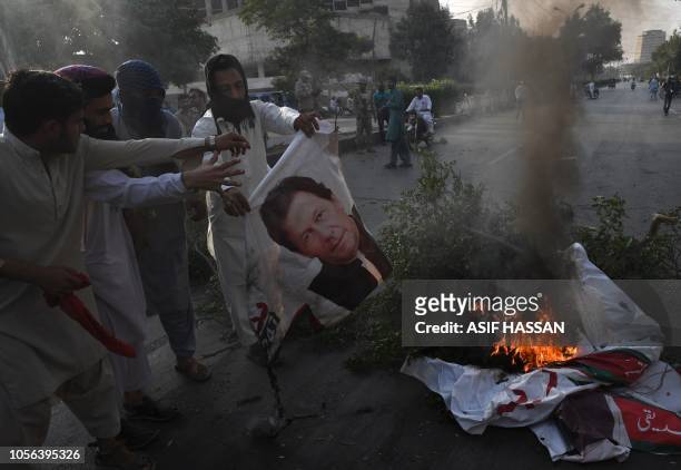Supporters of Pakistan's religious hardline party Jamiat Ulema Islam torch a poster of Pakistan's Prime Minister Imran Khan on a block street during...