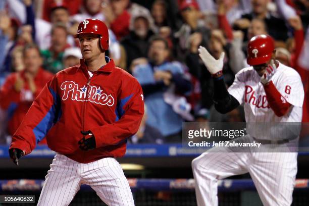 Roy Oswalt of the Philadelphia Phillies reacts as does teammate Ryan Howard after Oswalt slides home safely before the tag of Buster Posey of the San...