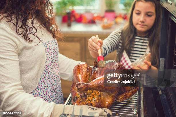 prepara el pavo para la cena de acción de gracias - bañar en su jugo durante la cocción fotografías e imágenes de stock