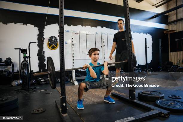 young boy lifting weights at gym while father watches - young kid and barbell stock-fotos und bilder