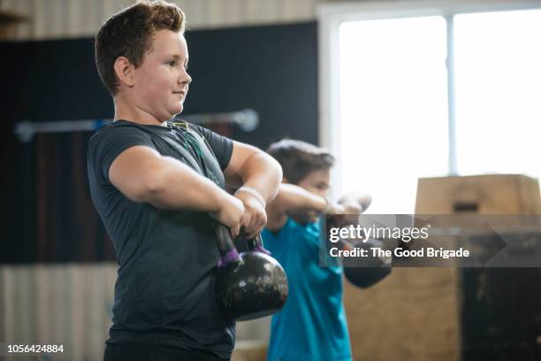 young boys lifting kettlebells at gym - weight lifting imagens e fotografias de stock