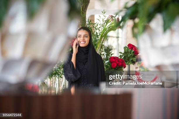 midden-oosten bloemist praten op mobiel, omgeven door bloemen, vazen - arab shopping stockfoto's en -beelden