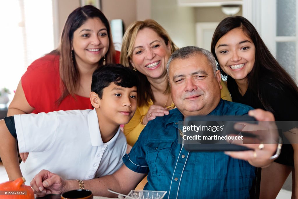 Three generations Latin American family taking selfie at meal time.