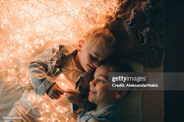 smiling kids tangled in christmas lights - tangled christmas lights stock pictures, royalty-free photos & images