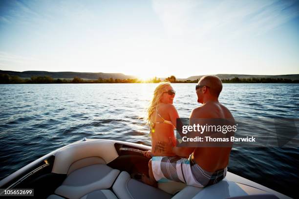 couple sitting on edge of bow of boat laughing - ships bow stock pictures, royalty-free photos & images