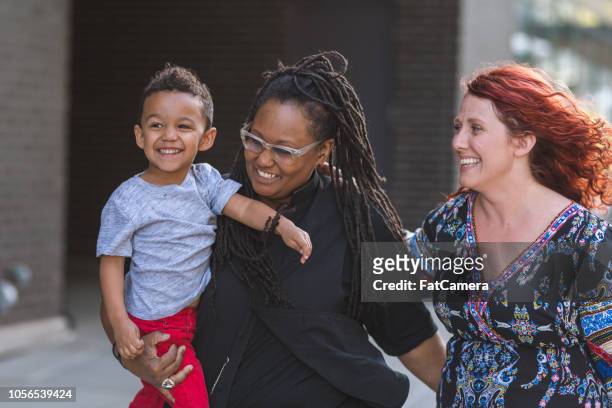female couple walking with their son - fat lesbian stock pictures, royalty-free photos & images