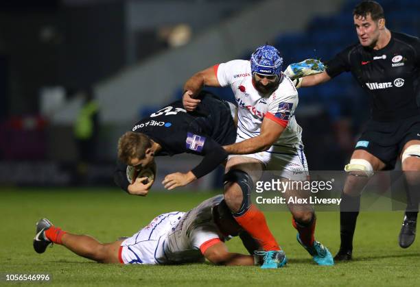 Max Malins of Saracens is tackled by Johnny Leota and Josh Strauss of Sale Sharks during the Premiership Rugby Cup match between Sale Sharks and...